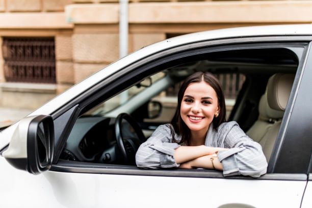 A young woman sitting in her new car smiling at the viewer