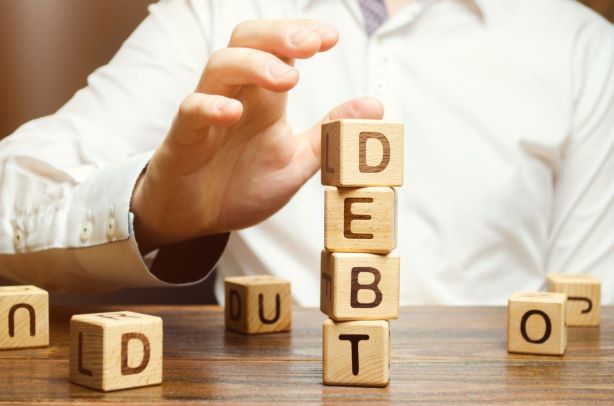 Stacked wooden blocks that spell out ’debt’