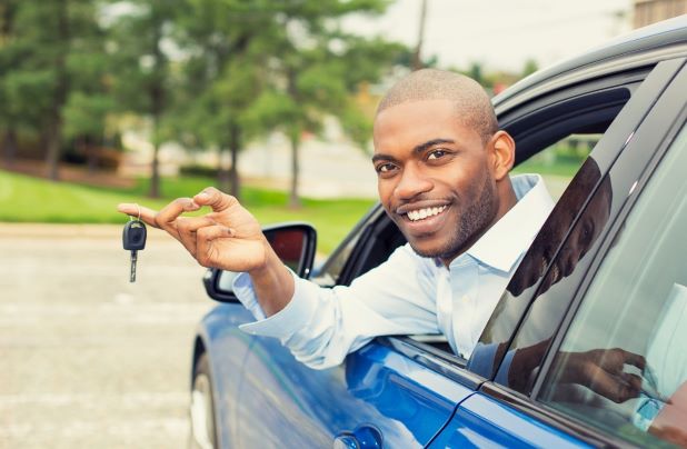 Man smiles holding keys to the new car he bought with a personal loan