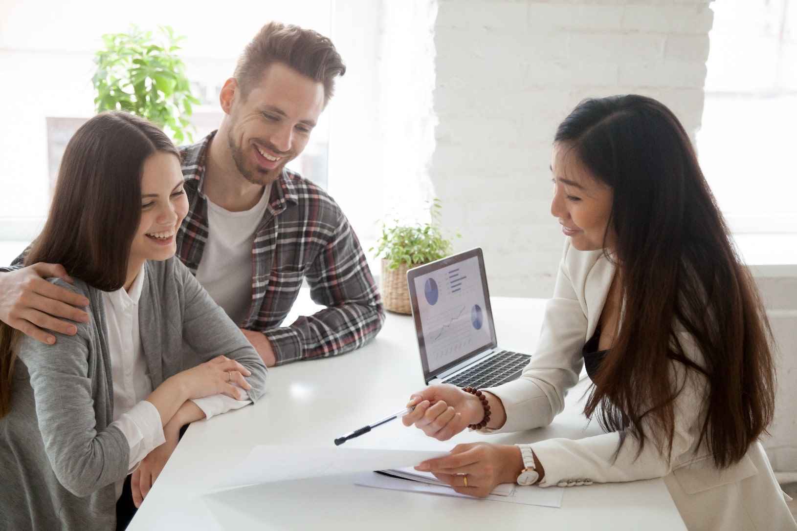 A young couple talking to a woman, approved for a loan thanks to their great credit rating