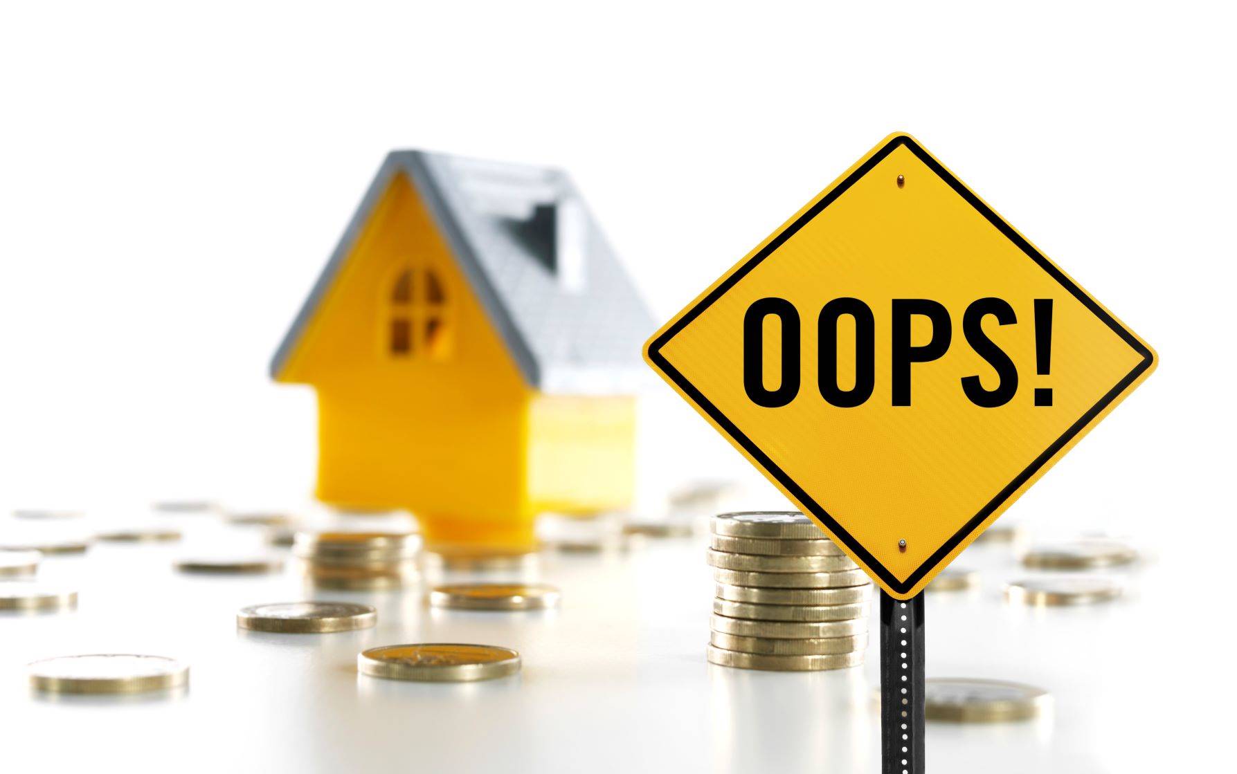 Yellow sign with word ‘Oops’ in front of a toy house and coins