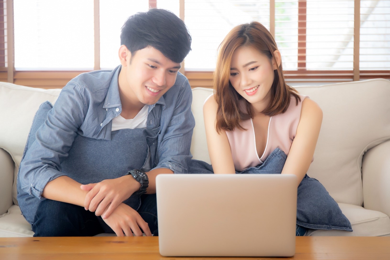 Young couple looking for a debt consolidation loan on their laptop in their living room