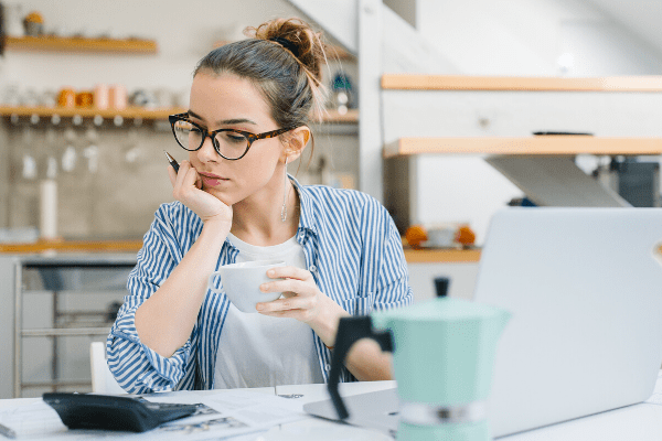 Woman planning a budget for Christmas with a calculator and a laptop in front of a table