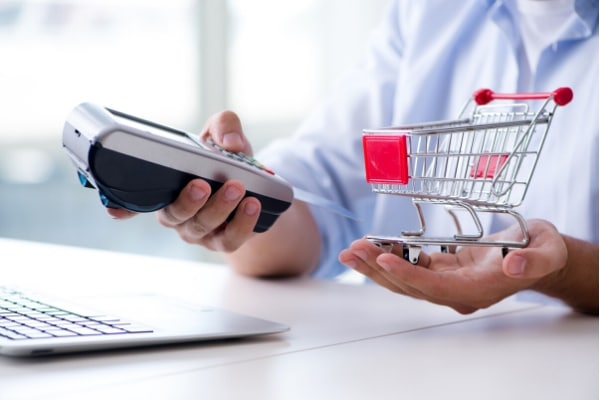 Man holding a cart and POS struggling to make payments for shopping purchases