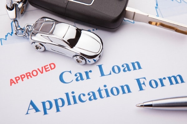 a car loan application form with a pen and car key