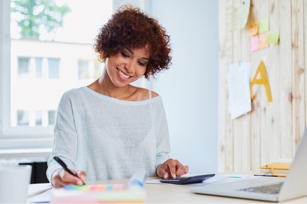 Happy woman working on a loan refinancing application with a calculator