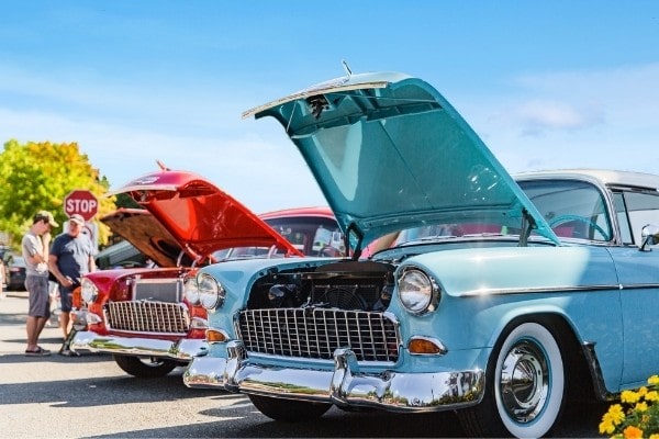 people checking out classic cars up for sale at the car yard