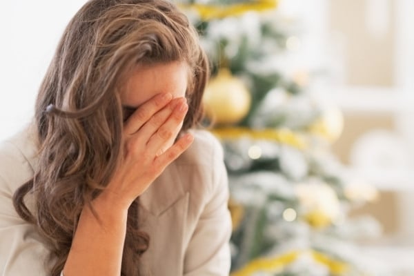 Stressed young woman in front of Christmas tree