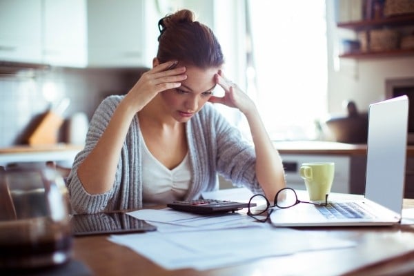 Close-up of a woman looking at a calculator and stressing about paying bills