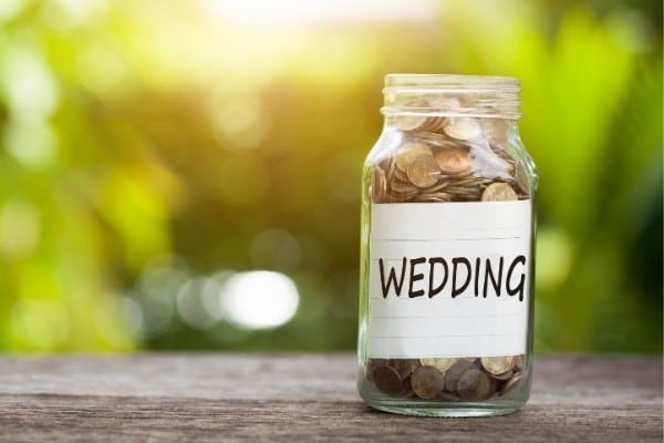 Word “wedding” with coins in glass jar