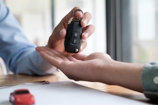 A car salesman handing the car key to a customer