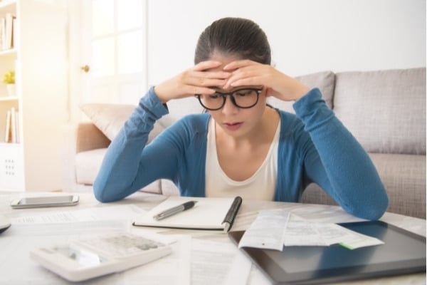 Woman looking at the total amount of the bills at home