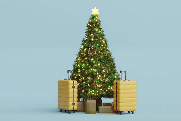 A Christmas tree with luggage placed around it.