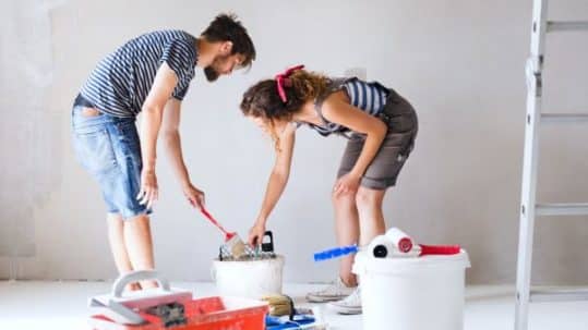 Young couple renovating their house and painting wall together