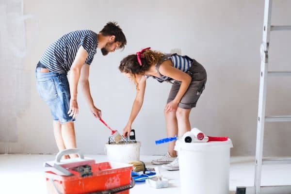 Young couple renovating their house and painting wall together